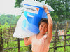 A woman smiles as she lifts up a water filter provided by World Vision.