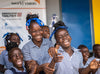 Schoolgirls wearing blue uniforms and blue hair ribbons laugh together.