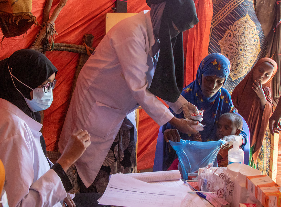 A woman and her two daughters receive medications from two female doctors in a mobile clinic.