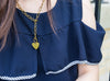 The torso of a long-haired girl wearing the heart pendant link necklace.