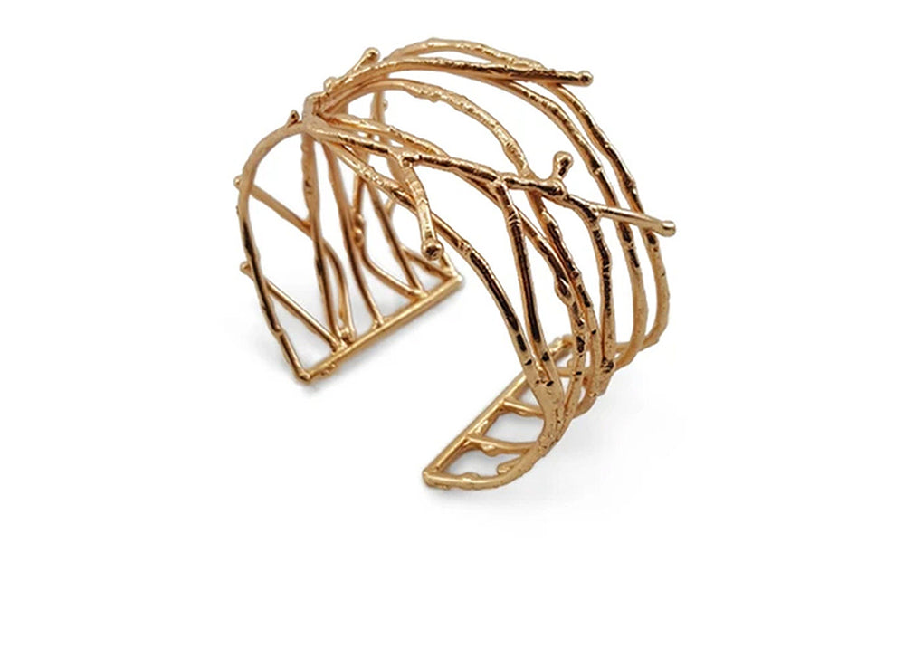 An adjustable cuff bracelet with twig designs in brass finish.