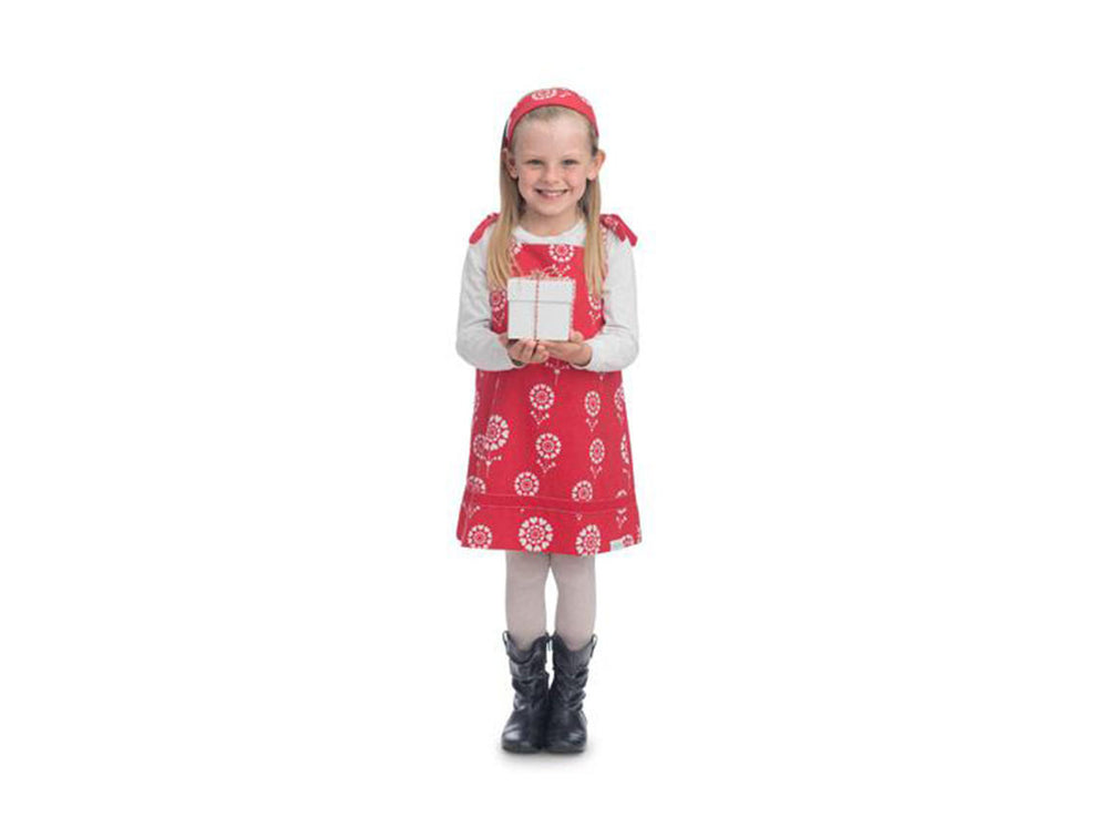 A young girl wearing a red dress and a pair of black boots smiles while holding a white box in her hands.
