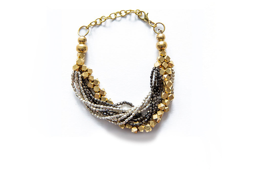 A multi-strand bracelet made of gold, black, and silver beads.