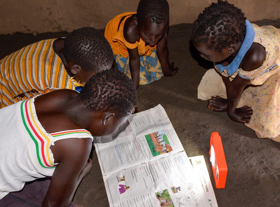 Four children huddle on the floor over a large, colourful worksheet.