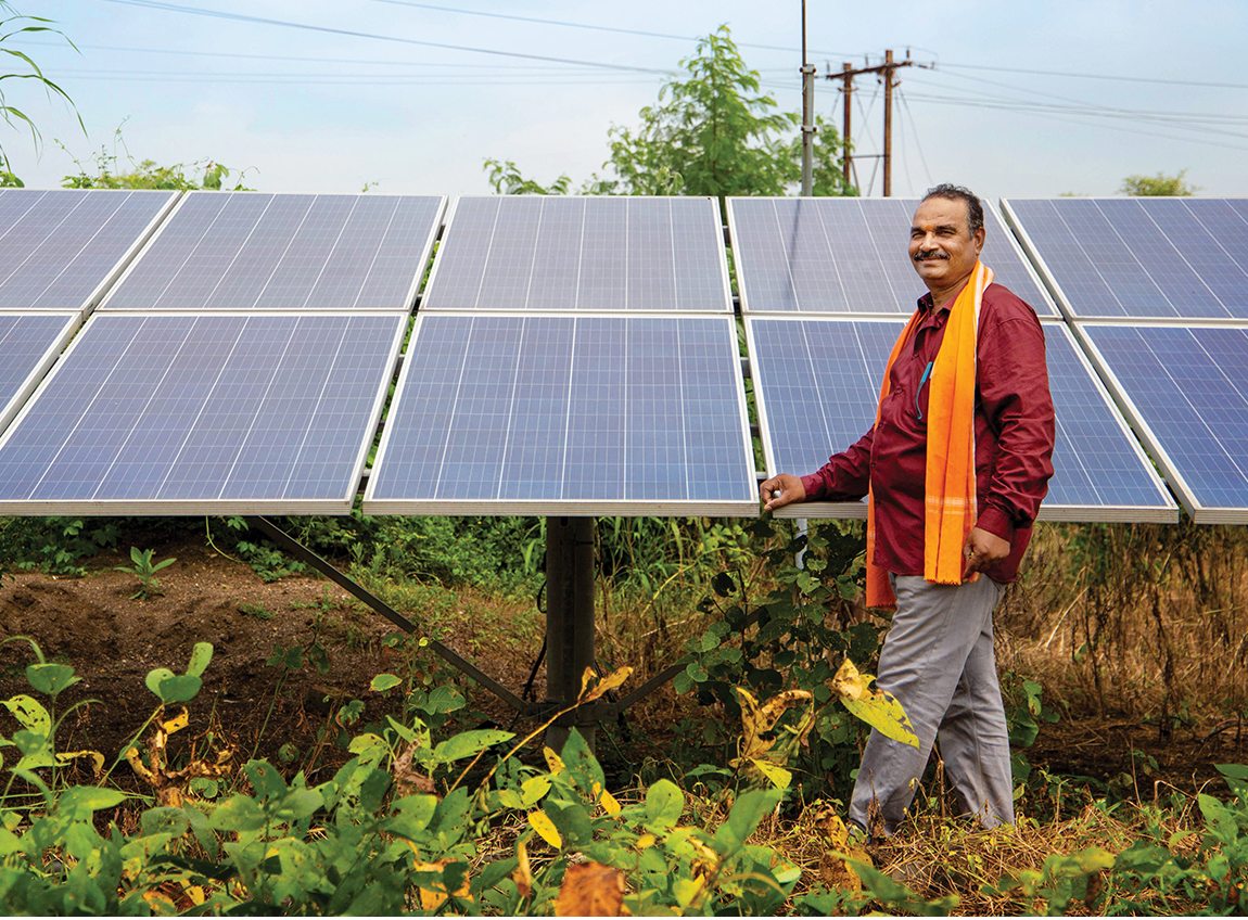 A man smiles as he shows off a bank of solar panels.